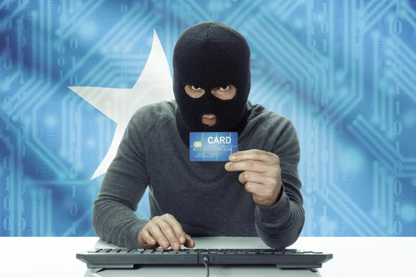 Dark-skinned hacker with flag on background holding credit card - Somalia —  Fotos de Stock