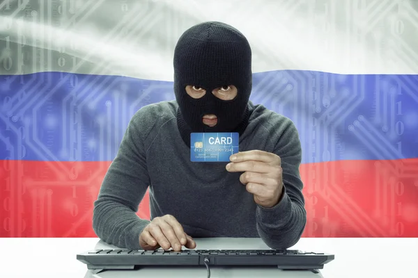 Dark-skinned hacker with flag on background holding credit card - Russia — 图库照片
