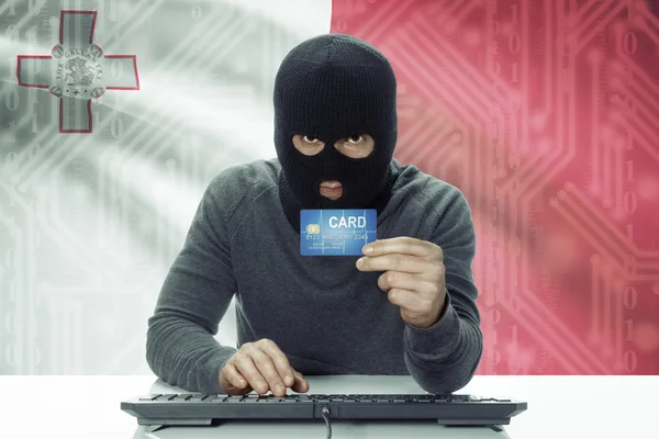 Dark-skinned hacker with flag on background holding credit card - Malta — Stock fotografie