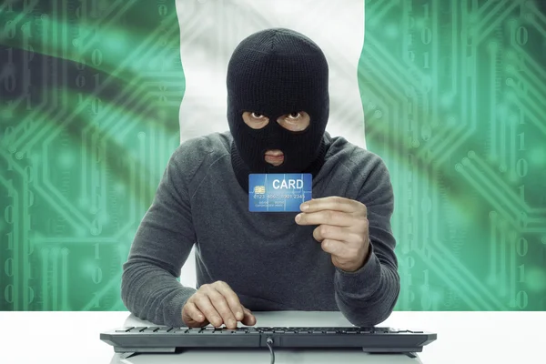 Dark-skinned hacker with flag on background holding credit card - Nigeria — Stock fotografie