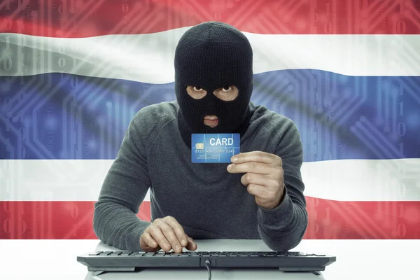Dunkelhäutige Hacker mit Flagge auf Hintergrund hält Kreditkarte - Thailand — Stockfoto