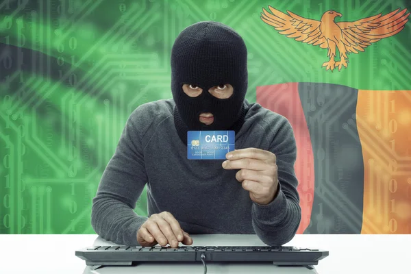 Dark-skinned hacker with flag on background holding credit card - Zambia — 图库照片
