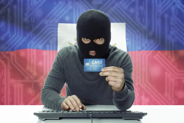 Dark-skinned hacker with flag on background holding credit card - Haiti — 图库照片