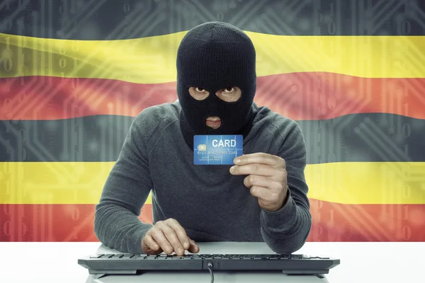 Dark-skinned hacker with flag on background holding credit card - Uganda — Zdjęcie stockowe