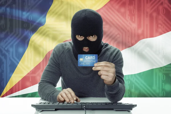 Dark-skinned hacker with flag on background holding credit card - Seychelles — Zdjęcie stockowe