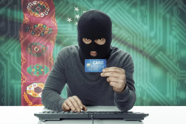 Dark-skinned hacker with flag on background holding credit card - Turkmenistan — Stock Photo, Image