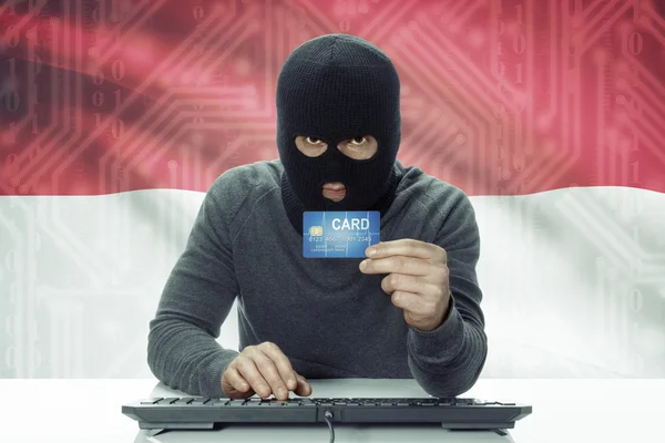 Dark-skinned hacker with flag on background holding credit card - Indonesia — Foto de Stock