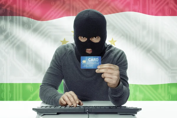 Dark-skinned hacker with flag on background holding credit card - Tajikistan — 图库照片