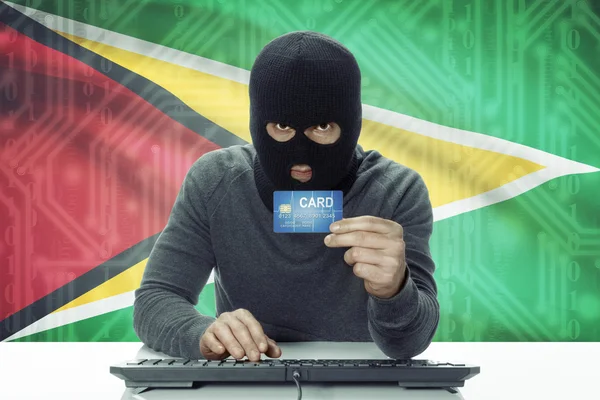 Dark-skinned hacker with flag on background holding credit card - Guyana — Foto de Stock