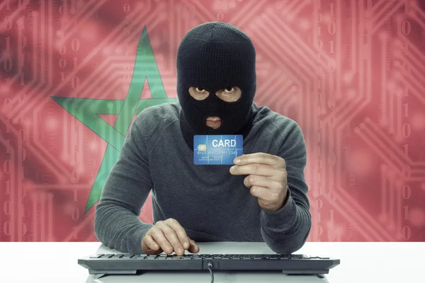 Dark-skinned hacker with flag on background holding credit card - Morocco — Stock Photo, Image