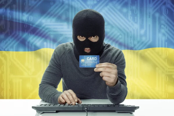 Dark-skinned hacker with flag on background holding credit card - Ukraine — 图库照片