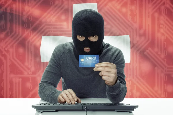 Dark-skinned hacker with flag on background holding credit card - Switzerland — Zdjęcie stockowe