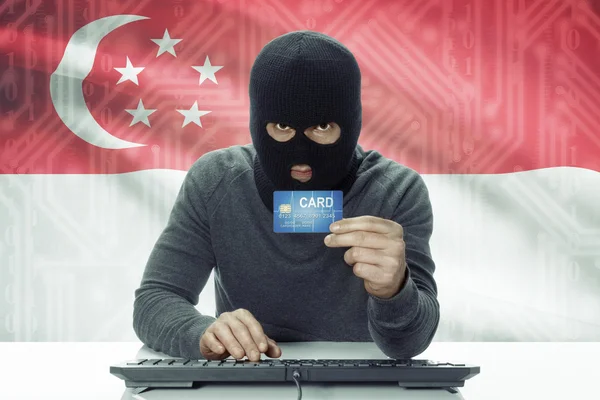 Dark-skinned hacker with flag on background holding credit card - Singapore — 스톡 사진