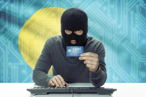 Dark-skinned hacker with flag on background holding credit card - Palau — Stock Photo, Image