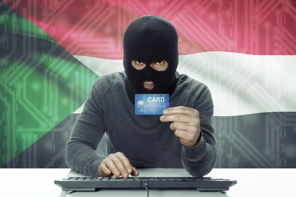 Dark-skinned hacker with flag on background holding credit card - Sudan — Stock Photo, Image