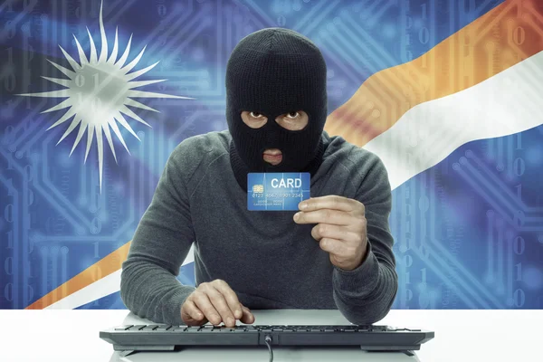 Dark-skinned hacker with flag on background holding credit card - Marshall Islands — Foto Stock