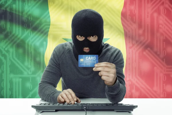 Dark-skinned hacker with flag on background holding credit card - Senegal — 图库照片