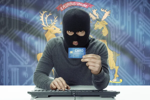 Dark-skinned hacker with USA states flag on background holding credit card - Michigan — стокове фото