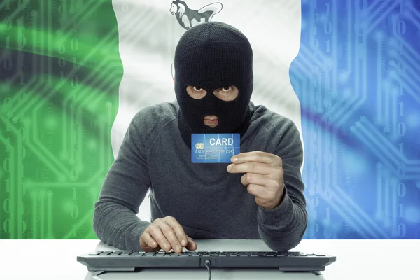 Dark-skinned hacker with Canadian province flag on background holding credit card - Yukon — Foto de Stock