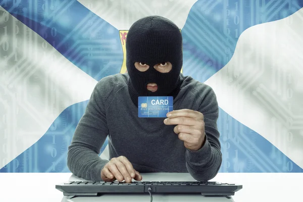 Dark-skinned hacker with Canadian province flag on background holding credit card - Nova Scotia — Stock fotografie