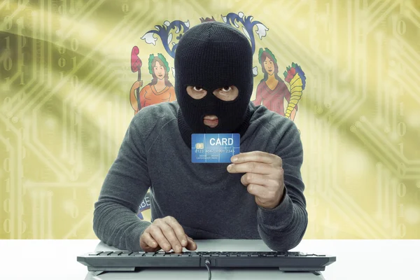 Dark-skinned hacker with USA states flag on background holding credit card - New Jersey — 스톡 사진