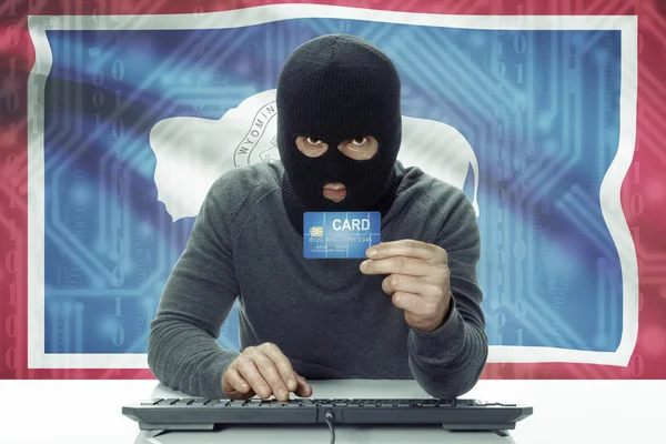 Dark-skinned hacker with USA states flag on background holding credit card - Wyoming — 图库照片