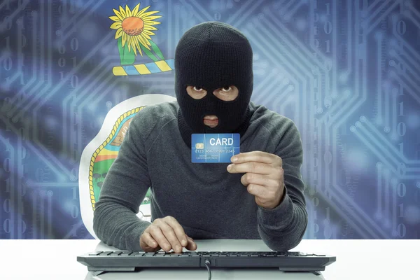 Dark-skinned hacker with USA states flag on background holding credit card - Kansas — стокове фото