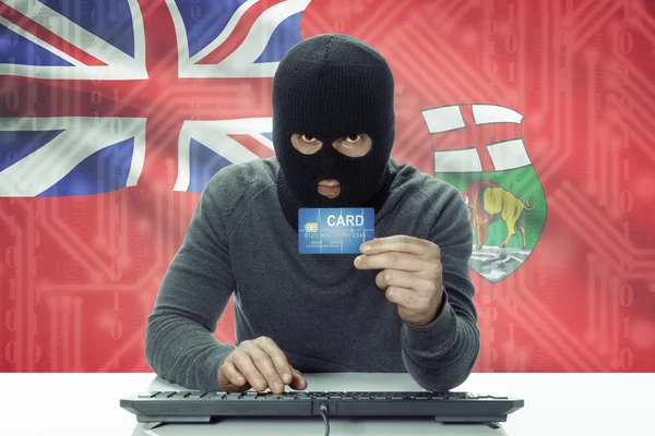 Dark-skinned hacker with Canadian province flag on background holding credit card - Manitoba —  Fotos de Stock