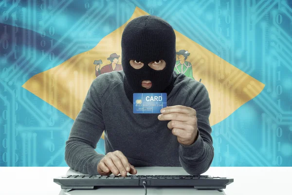 Dark-skinned hacker with USA states flag on background holding credit card - Delaware — Stock Photo, Image