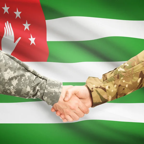 Men in uniform shaking hands with flag on background - Abkhazia — Stock Photo, Image