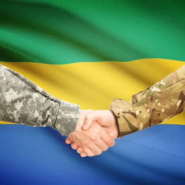 Mannen in uniform schudden handen met vlag op achtergrond - Gabon — Stockfoto