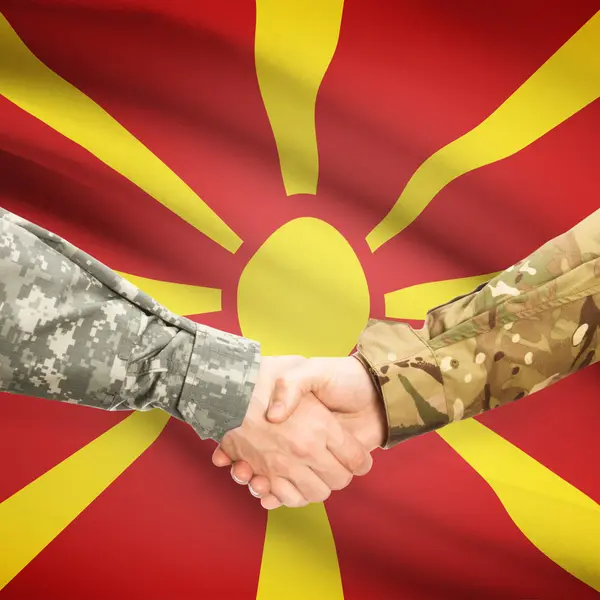 Люди в форме, пожимая руки с флагом на фоне - Македония — стоковое фото