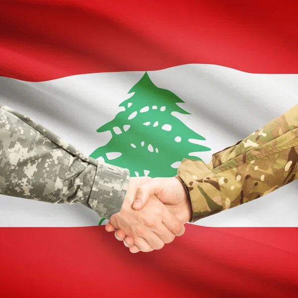 Men in uniform shaking hands with flag on background - Lebanon - Stock-foto