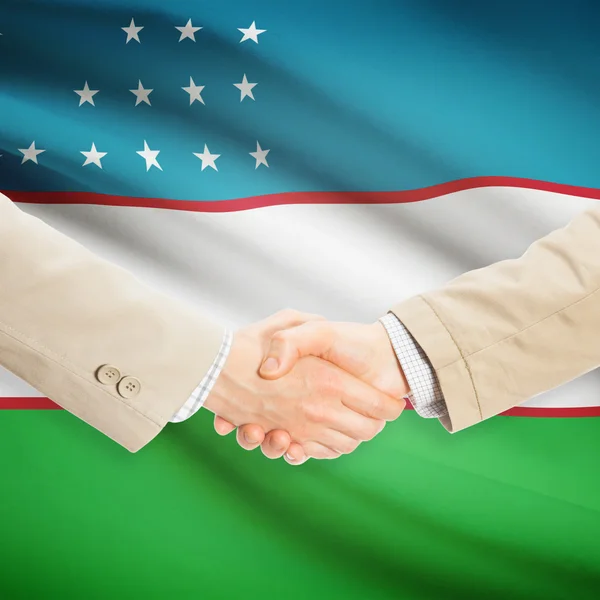 Businessmen handshake with flag on background - Uzbekistan — Stock Photo, Image