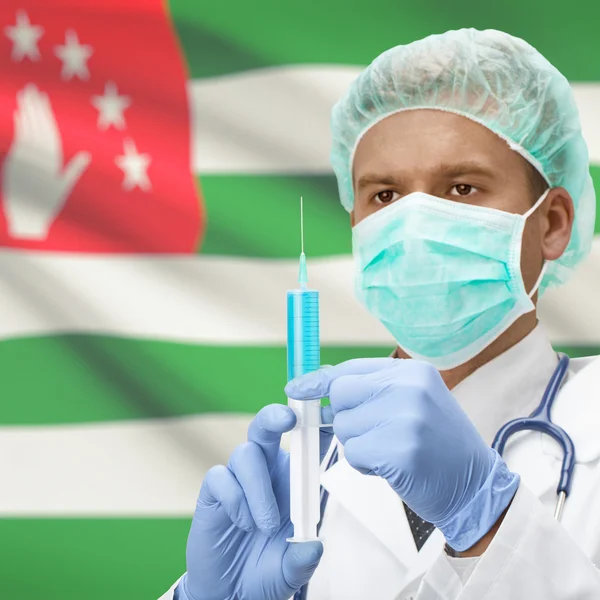 Médico con jeringa en las manos y la bandera de la serie - Abjasia —  Fotos de Stock