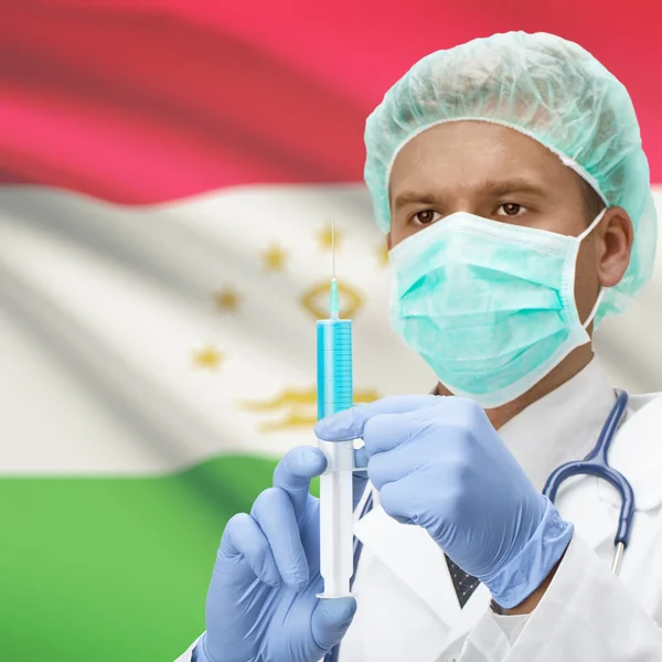 Médico con jeringa en las manos y la bandera de la serie - Tayikistán — Foto de Stock