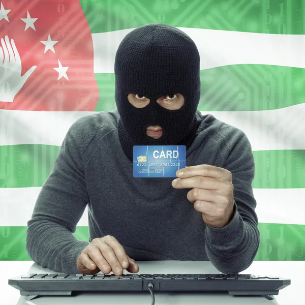 Dark-skinned hacker with flag on background holding credit card in hand - Abkhazia — Foto de Stock