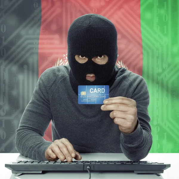 Dark-skinned hacker with flag on background holding credit card in hand - Afghanistan — Stock fotografie