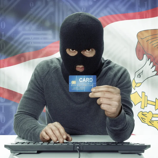 Dark-skinned hacker with flag on background holding credit card in hand - American Samoa - Stock-foto