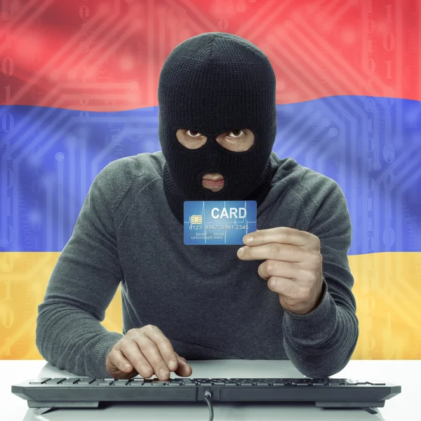 Dark-skinned hacker with flag on background holding credit card in hand - Armenia — 图库照片
