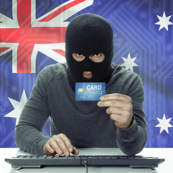 Dark-skinned hacker with flag on background holding credit card in hand - Australia — Stock Photo, Image