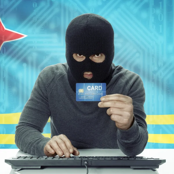 Dark-skinned hacker with flag on background holding credit card in hand - Aruba — Zdjęcie stockowe