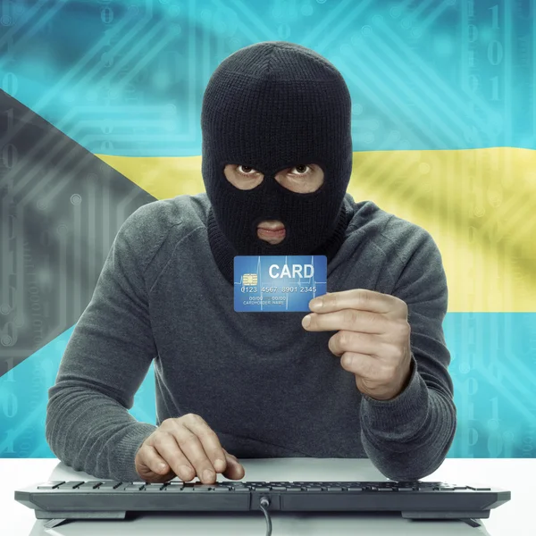 Dark-skinned hacker with flag on background holding credit card in hand - Bahamas — 图库照片