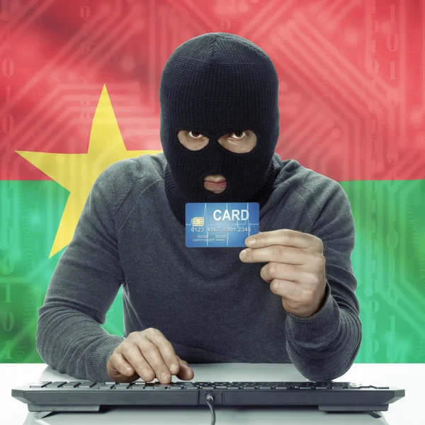 Dark-skinned hacker with flag on background holding credit card in hand - Burkina Faso — Zdjęcie stockowe