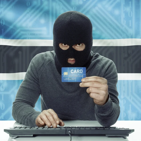 Dark-skinned hacker with flag on background holding credit card in hand - Botswana — Stockfoto