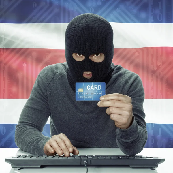 Dark-skinned hacker with flag on background holding credit card in hand - Costa Rica — Foto de Stock