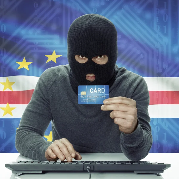 Dark-skinned hacker with flag on background holding credit card in hand - Cape Verde — 图库照片