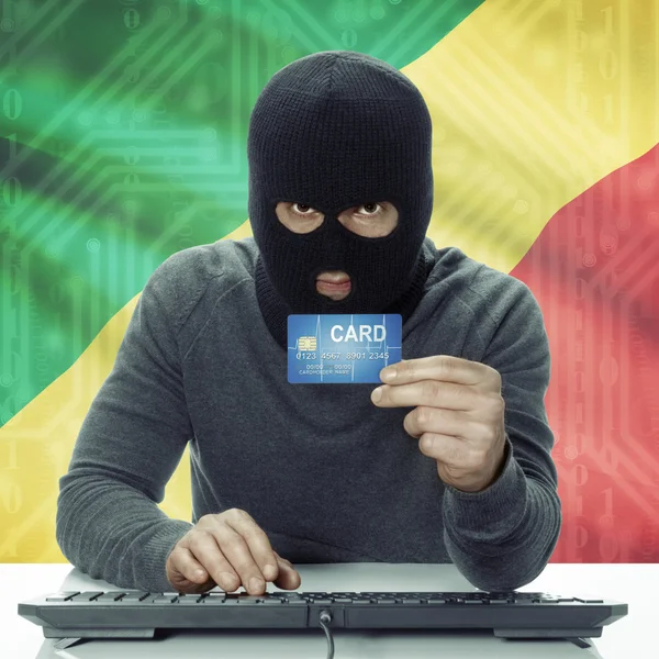 Dark-skinned hacker with flag on background holding credit card in hand - Congo-Brazzaville — Stockfoto