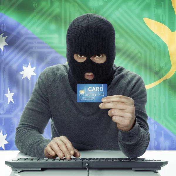Dark-skinned hacker with flag on background holding credit card in hand - Christmas Island — Stock Photo, Image
