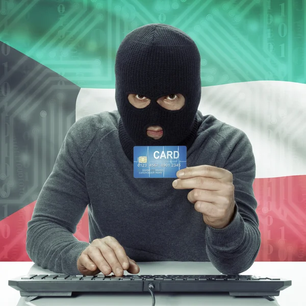 Dark-skinned hacker with flag on background holding credit card in hand - Kuwait — Stock Photo, Image